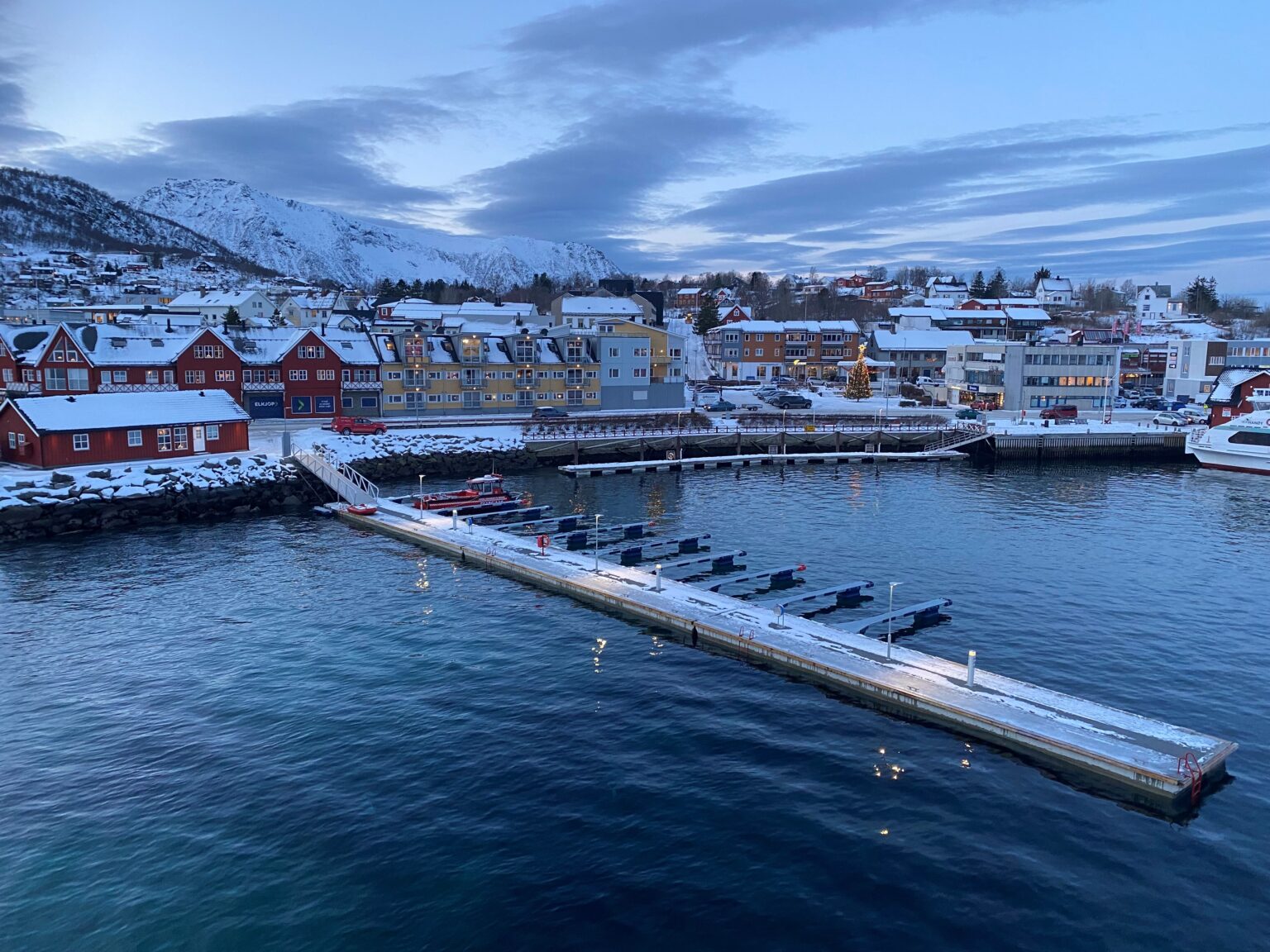 Bilde av gjestebryggen i Stokmarknes havn en fin vinterdag i skumringstimen.